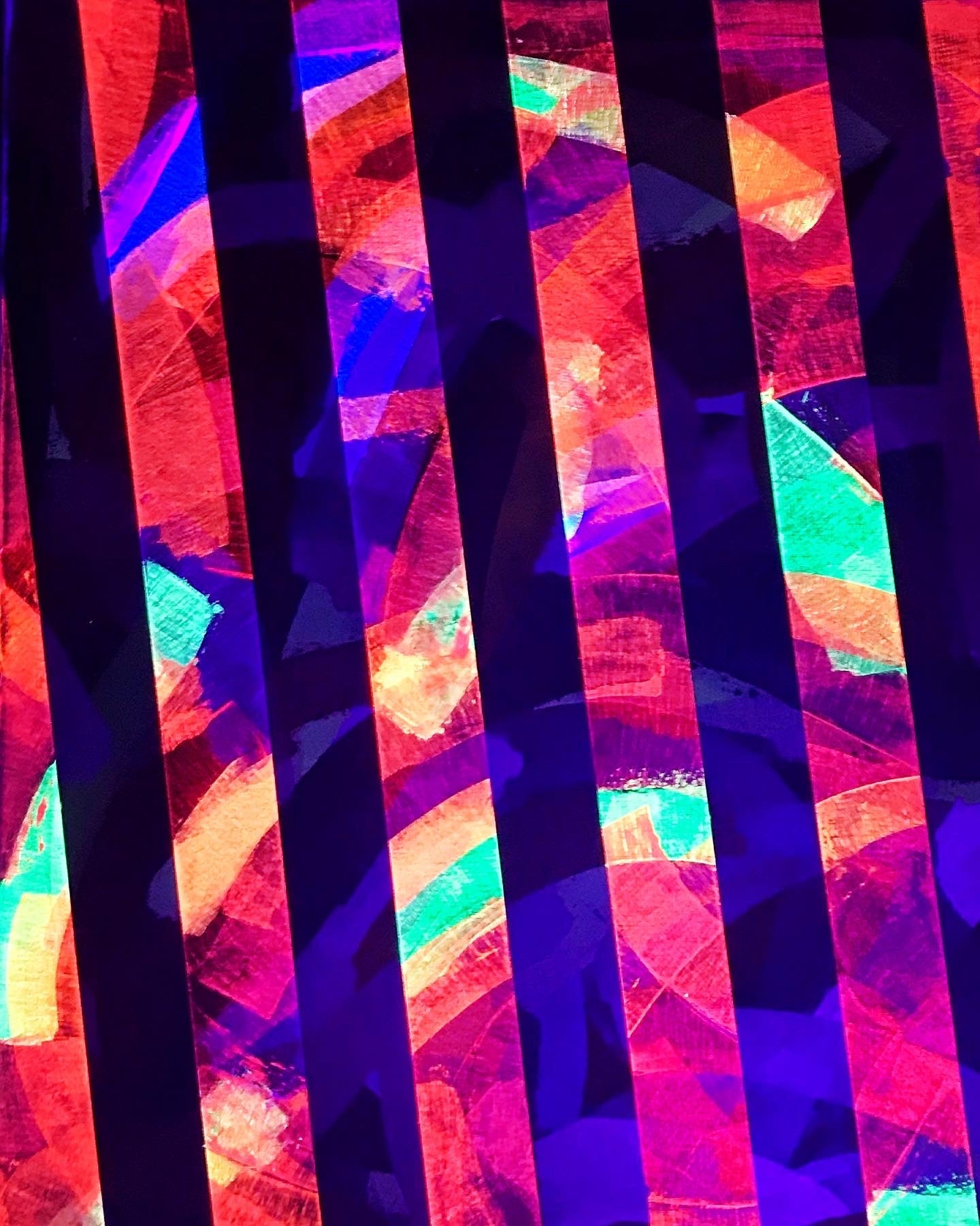 Metallic and fluorescent acrylics painting with colorful stripes, under UV light